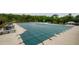 View of community pool with a safety cover, surrounded by lounge chairs and tables for outdoor relaxation at 4380 Serenity Lake Dr, Cumming, GA 30028