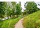 Picturesque walking trail surrounded by lush greenery and tall trees, leading to a tranquil lake view at 4380 Serenity Lake Dr, Cumming, GA 30028