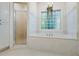 Elegant bathroom featuring a soaking tub, glass-block window, and tiled walls at 915 Rocky Creek Rd, Hampton, GA 30228