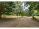 Spacious front yard with long paved driveway, lush landscaping, and mature trees at 915 Rocky Creek Rd, Hampton, GA 30228