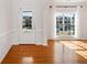 Bright entryway featuring hardwood floors, a large window with white curtains, and a classic white door at 5819 Rue Chase Way, Tucker, GA 30084