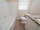 Bathroom featuring tiled bath surround, window providing natural light, and granite countertop at 2104 Barbara Ln, Decatur, GA 30032