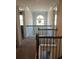 Carpeted hallway with iron railing, chandelier, and natural lighting at 2208 Ginger Lake Ne Dr, Conyers, GA 30013