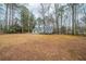 Backyard view highlighting a spacious lawn, mature trees, and a charming house with a wooden deck at 270 Merrydale Dr, Fayetteville, GA 30215