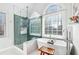 Modern bathroom with glass shower and soaking tub near a large window at 1302 Turtlebrook Ln, Lawrenceville, GA 30043