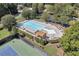 Aerial view of a resort-style pool area with lounge chairs, pergola, and lush landscaping near tennis courts at 1302 Turtlebrook Ln, Lawrenceville, GA 30043