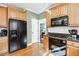 Kitchen featuring wooden cabinetry, black appliances, and granite countertops at 1302 Turtlebrook Ln, Lawrenceville, GA 30043