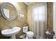 Cozy half bathroom featuring patterned wallpaper, round silver mirror, white sink and toilet at 296 Cedar Bay Cir, Dallas, GA 30157