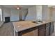 Kitchen island with stainless steel dishwasher, countertops and dark cabinets, open to living room with fireplace at 7889 Winkman Dr, Fairburn, GA 30213