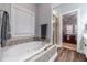 Luxurious soaking tub next to a window in a stylish bathroom with wood-look floors at 217 Chad Ln, Loganville, GA 30052