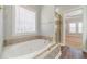 Elegant bathroom with a large soaking tub, stylish tile surround, and separate glass-enclosed shower at 217 Chad Ln, Loganville, GA 30052