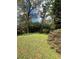 Backyard with large trees, lush shrubbery, and green grass at 5157 West St, Covington, GA 30014