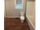 Bathroom with a toilet and tiled shower/tub with wood-look floors at 5157 West St, Covington, GA 30014