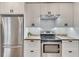 Modern kitchen with stainless steel refrigerator, oven, white cabinetry, and geometric backsplash at 5833 Westerling Pl, Powder Springs, GA 30127