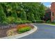 Lush landscaping surrounds the property, featuring trees, shrubs, and colorful flowers next to a paved driveway at 5964 Reddington Way, Sandy Springs, GA 30328