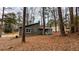 This home is nestled amongst mature trees with gray siding and white trim at 3515 Weathered Wood Dr, Ellenwood, GA 30294