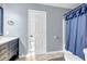 Well-lit bathroom with white door, blue accents, and shower curtain at 5806 Highgrove Dr, Atlanta, GA 30349
