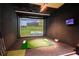 Indoor golf simulator room with a large screen, putting green, and golf clubs for practice at 4561 Olde Perimeter Way # 2707, Atlanta, GA 30346