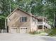 A tan house featuring a two-car garage, covered porch and mature landscaping in a wooded setting at 4422 Fincher Rd, Canton, GA 30114