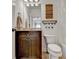 A cozy half-bathroom with rustic brown cabinets, a toilet, and a framed sign at 5760 Windjammer Pt, Cumming, GA 30041