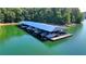 Aerial view of covered boat dock featuring multiple boat slips and a walkway in a serene lake setting at 5760 Windjammer Pt, Cumming, GA 30041