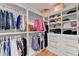 A large walk-in closet with custom shelving, hanging racks, and a hardwood floor at 5760 Windjammer Pt, Cumming, GA 30041