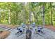 Chairs around a fire pit surrounded by trees in beautiful landscaped yard at 5760 Windjammer Pt, Cumming, GA 30041