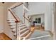 Bright foyer features hardwood floors, elegant staircase, and view into home office at 5760 Windjammer Pt, Cumming, GA 30041