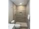 A remodeled bathroom showcasing a walk-in shower with tiled walls, a speckled shower base, and modern fixtures at 1055 Pinecrest Dr, Forest Park, GA 30297