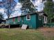 Exterior view of a home featuring a green facade, a small deck, and a spacious yard at 5325 Victory Blvd, Morrow, GA 30260