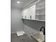 Well-lit laundry room featuring ample white cabinet storage above a utility sink and gray tile floor at 676 S Grand Nw Ave, Atlanta, GA 30318