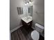 Bathroom showcases a vanity with sink, framed mirror, toilet and wood-look floors at 7214 Bedrock Cir, Lithonia, GA 30038