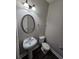 Updated powder room with modern fixtures, oval mirror, and dark wood floors at 7214 Bedrock Cir, Lithonia, GA 30038