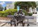 A lifelike sculpture of an elderly couple seated on a park bench in a landscaped outdoor setting at 10 Clarke Hill St, Decatur, GA 30030