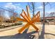 A striking yellow geometric sculpture stands prominently in an outdoor public space near a pedestrian walkway at 10 Clarke Hill St, Decatur, GA 30030