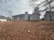 Back exterior view of the home with a large backyard covered in fallen leaves at 40 Brandon Dr, Covington, GA 30016