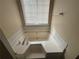 A close-up of a beige soaking tub with tile surround and a window with blinds for natural light at 40 Brandon Dr, Covington, GA 30016