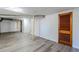 Finished basement with grey wood-look floors, painted walls and ceiling, plus a wooden door at 1722 Detroit Nw Ave, Atlanta, GA 30314