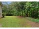 Manicured backyard surrounded by mature trees and lush greenery offers privacy and space for outdoor activities at 4156 Holly Springs Rd, Rockmart, GA 30153