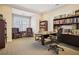 Well-lit home office with bookshelves, two sitting chairs, large desk, and neutral carpeting at 23310 Plantation Dr, Atlanta, GA 30324