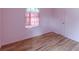 Bedroom features hardwood floors, a window with pink curtains, and a built-in closet at 301 Lady Agatha Ct, Jonesboro, GA 30236