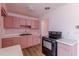 An image of a kitchen featuring pink cabinets, electric oven, wood floor, and white countertop at 301 Lady Agatha Ct, Jonesboro, GA 30236