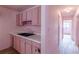 View of the kitchen area showcasing pink cabinets, double basin sink, and access to hallway at 301 Lady Agatha Ct, Jonesboro, GA 30236