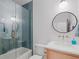 Modern bathroom features stylish blue tile in the shower and a round mirror above the vanity at 650 Jones Rd, Roswell, GA 30075