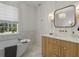 Bright bathroom with a soaking tub, white walls, decorative mirror, and striking vanity at 650 Jones Rd, Roswell, GA 30075