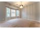 Spacious bedroom featuring neutral carpet, three bright windows and a decorative hanging light fixture at 2430 Bretdale Rd, Duluth, GA 30096