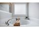 Relaxing bathroom featuring a soaking tub with a wooden bath caddy and frosted glass window at 5355 Avonshire Ln, Cumming, GA 30040