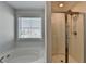 Bright bathroom featuring a soaking tub with window and a glass-enclosed shower with chrome fixtures at 1883 Frisco Way, Suwanee, GA 30024
