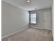 Neutral bedroom featuring plush carpet, a bright window, and a gray-painted door at 1883 Frisco Way, Suwanee, GA 30024