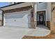 Home exterior showcasing an attached two-car garage with brick accents and a covered front porch at 1883 Frisco Way, Suwanee, GA 30024